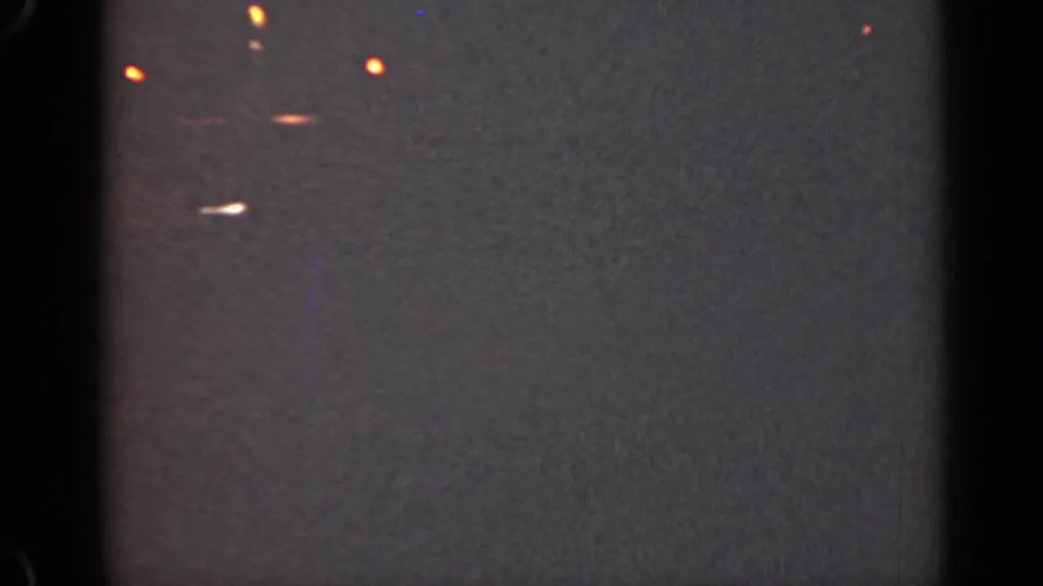 1947 Illinois 8mm frame showing darkness, film borders, grain, and clustered orange-white light streaks near the left edge.
