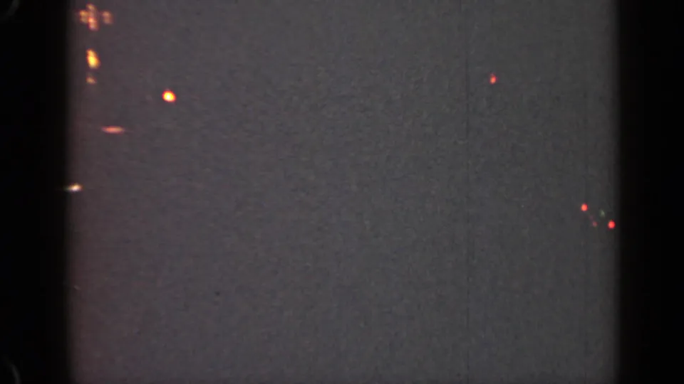 1947 Illinois 8mm frame showing faint out-of-focus nighttime lights against a dark gray grainy field.