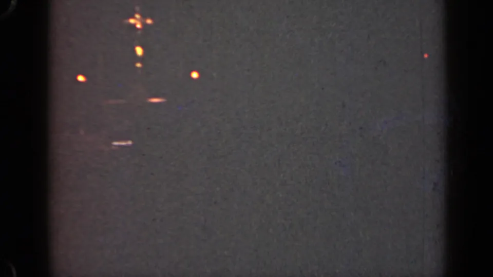 1947 Illinois 8mm frame with scattered soft lights, dark exposure, and visible film artifacts near the frame edges.