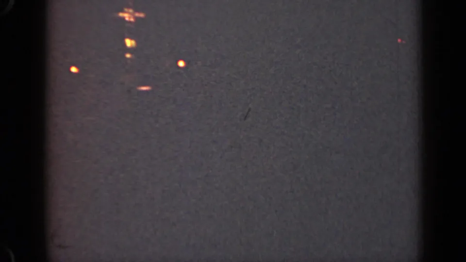 1947 Illinois 8mm footage frame with blurred orange vessel lights and visible low-light film texture.