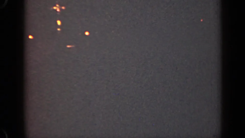 1947 Illinois 8mm frame showing distant orange lights, likely from a ship or boat, in a dark night view.