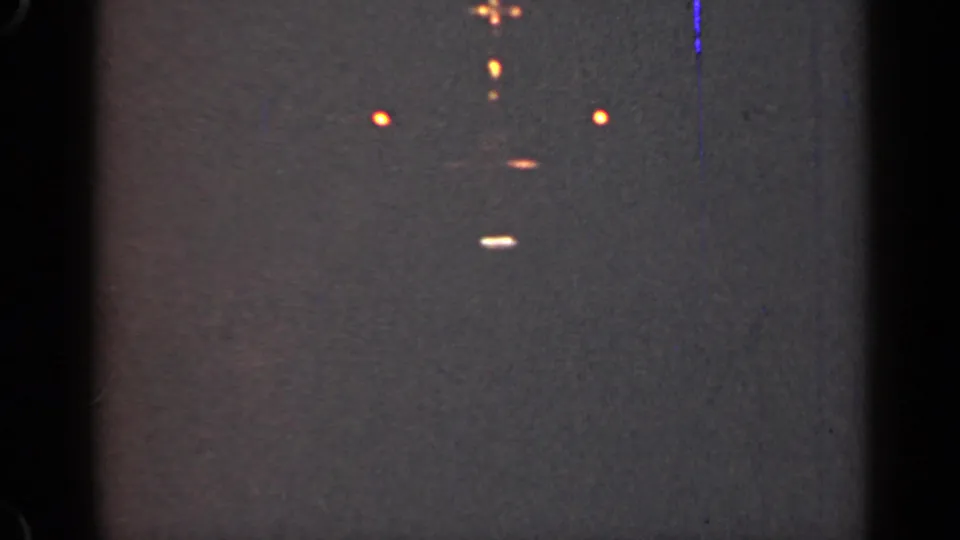 1947 Illinois 8mm frame showing faint orange light points against a dark gray textured field with visible film borders and wear.