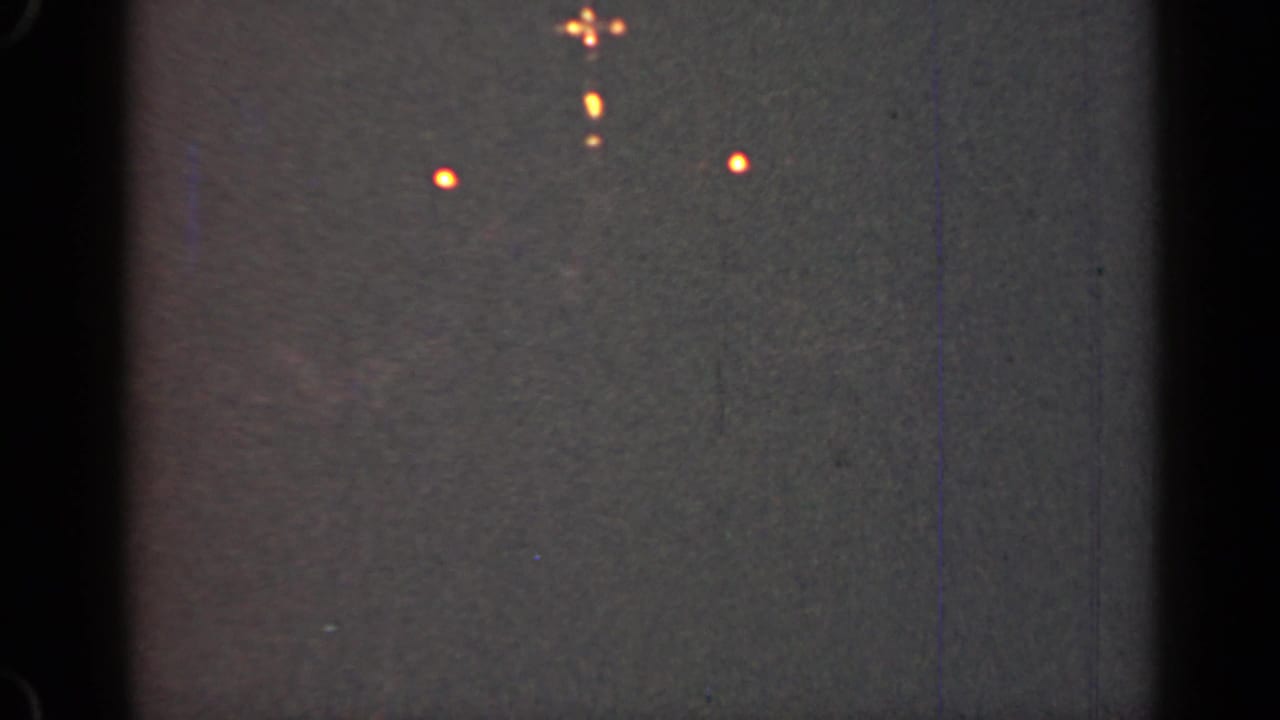 Dark sky with several orange points of light and film-edge shadows.