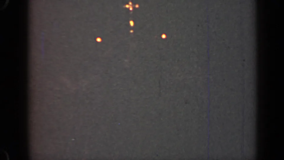 1947 Illinois 8mm frame showing small orange lights against a dark, grainy night sky with visible film wear.