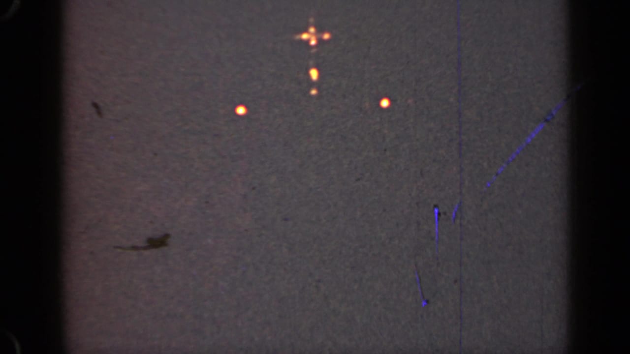Orange lights and a small glowing cluster on a dark scratched sky field.