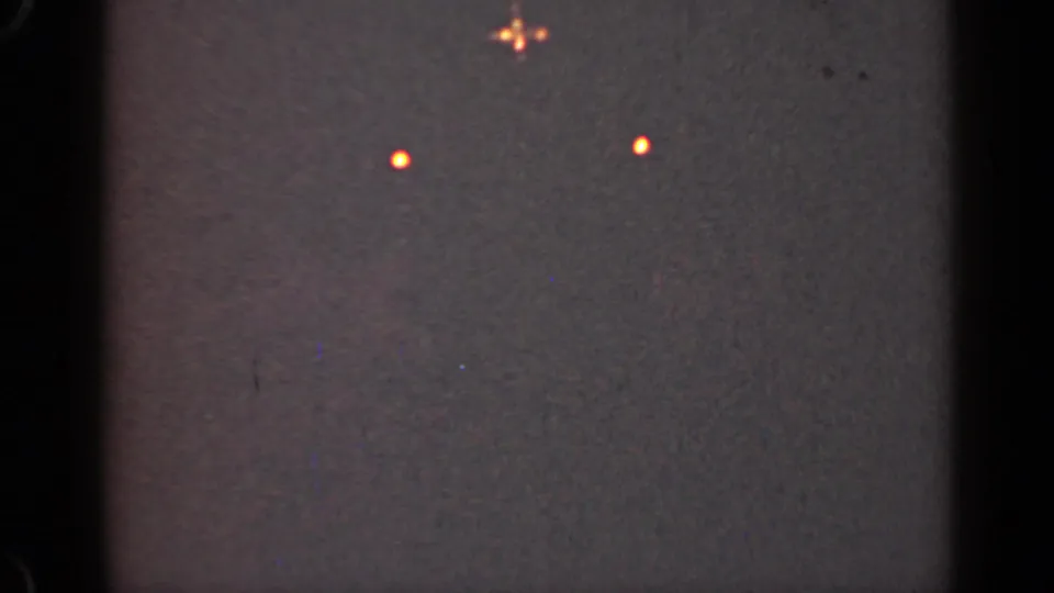 1947 Illinois 8mm frame showing two orange lights below a small glowing cluster, with scratches and muted exposure.