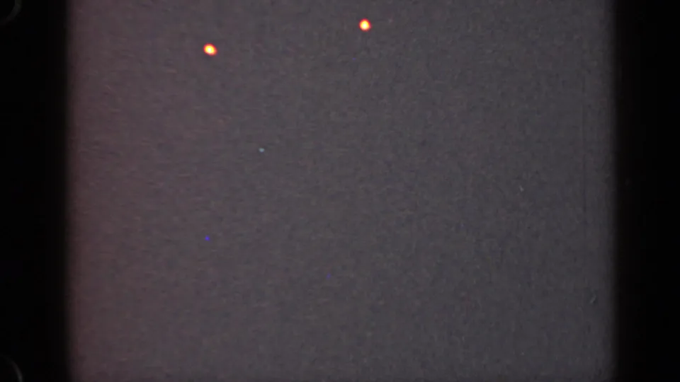 1947 Illinois 8mm frame with two small orange lights against a dark, heavily grained night sky and faint film marks.