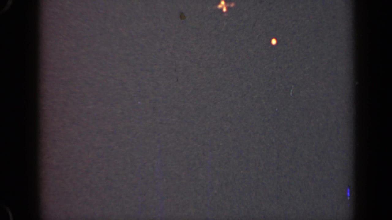 Dark textured frame with central black divider, orange speck near the top, and scattered dust.