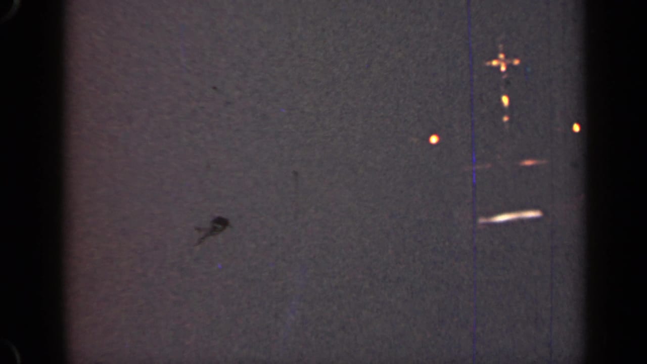 Dark bands cross a gray textured field with orange flares and dust marks.