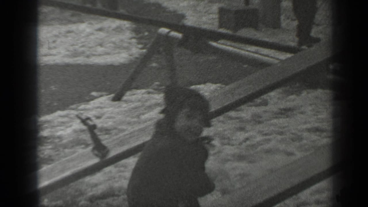 Small bundled child on a wooden seesaw in a snowy park.