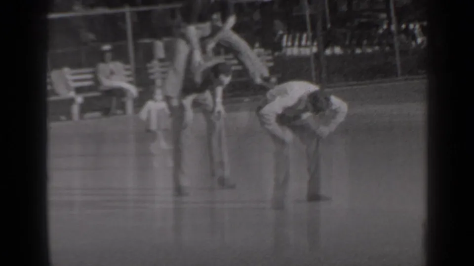 In 1947 New York home-movie footage, three young men play leapfrog on grass near benches, trees, and a park fence.