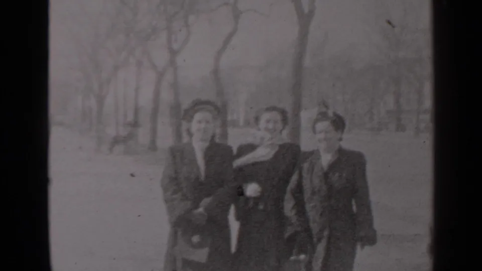 Three adult women in late-1940s coats and hats walk together in a New York park-like setting, with bare trees behind them.