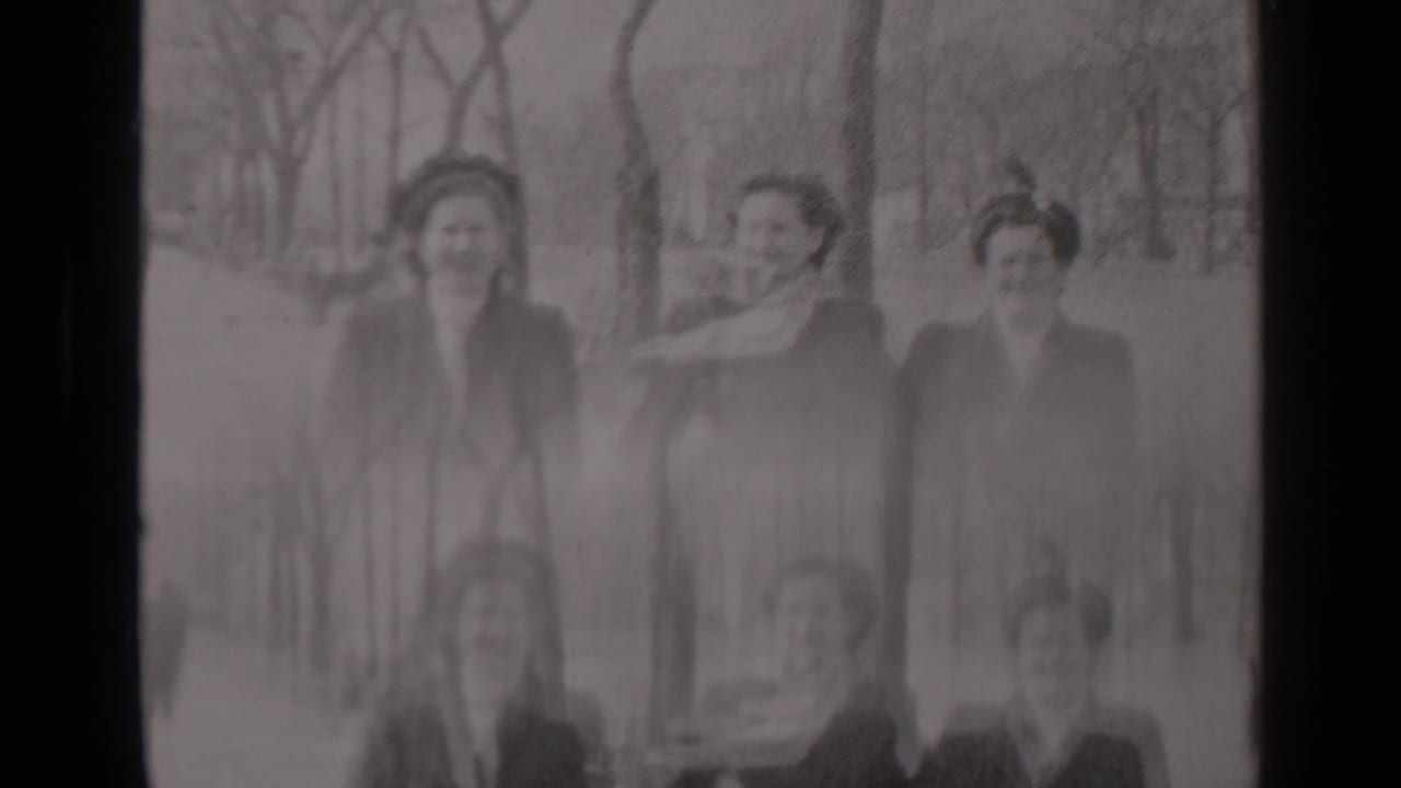 Three women continue walking as a scarf blows across the middle woman’s face.