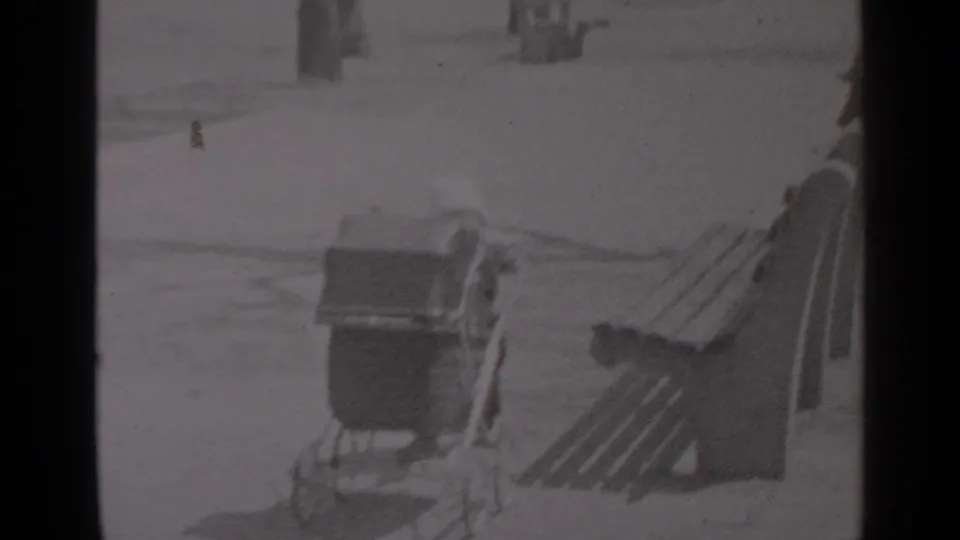 A small bundled figure appears beside a vintage baby carriage near wooden benches in a snowy New York park scene.
