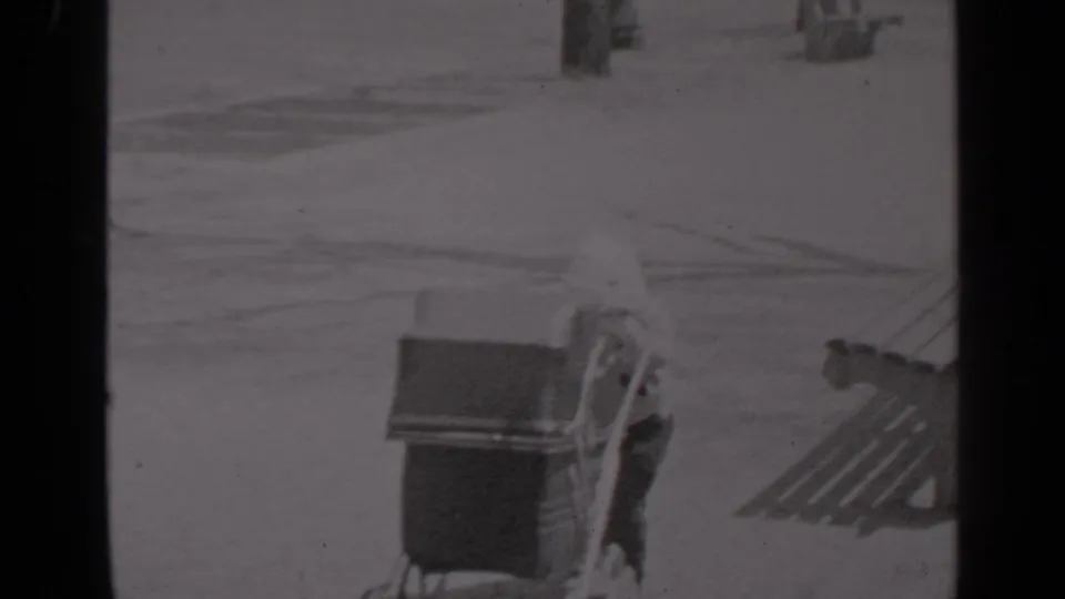 A small figure is partly visible beside a vintage baby carriage near wooden benches in the 1947 New York park footage.