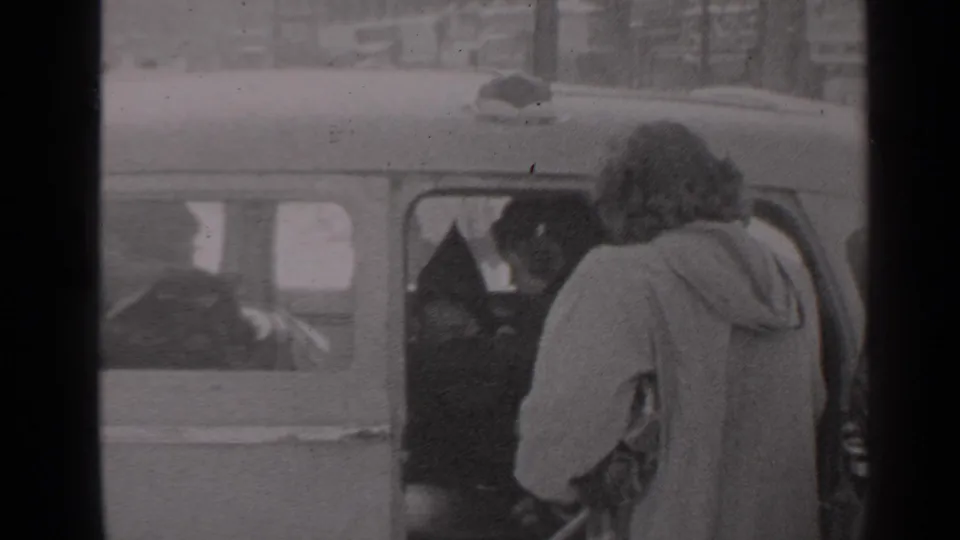 1947 New York home-movie frame showing a woman bending toward the open rear car door during a family departure.