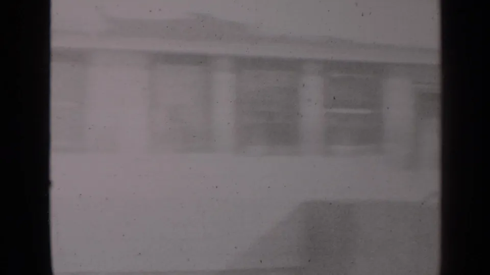 Blurred 8mm view of the snowy yard and house exterior in the 1947 New York winter family scene.