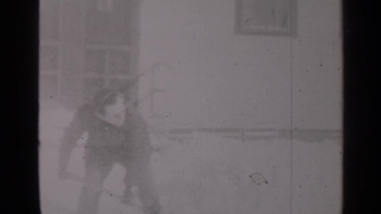 Bundled person near a snowy residential building facade.