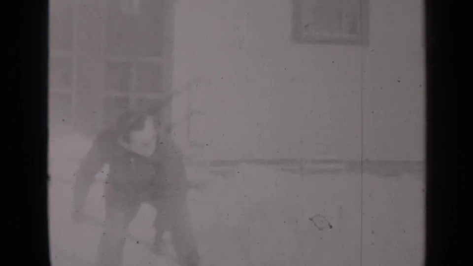 1947 New York home-movie frame showing a bundled figure near snow and apartment-style windows.