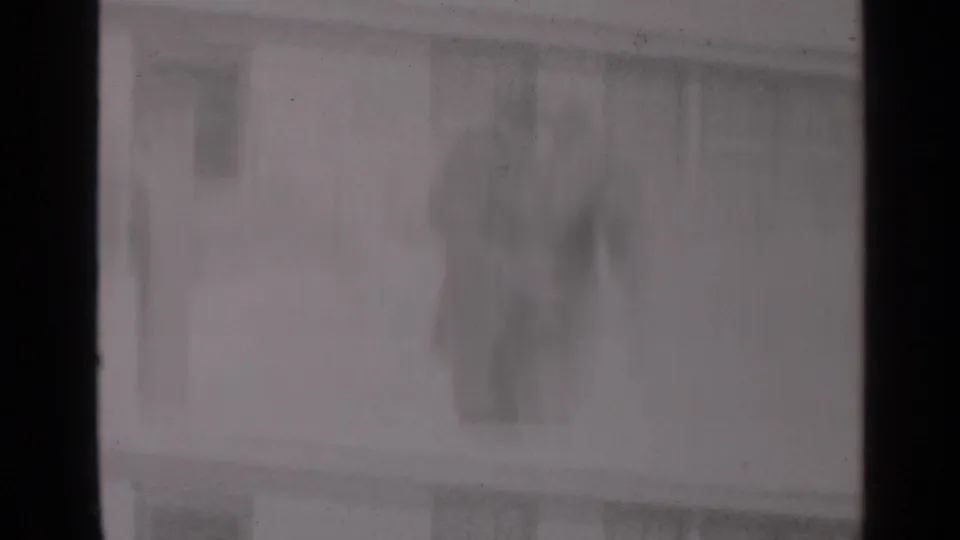 Soft 8mm frame of a snowy New York residential building, with windows and dark vertical frame edges visible.