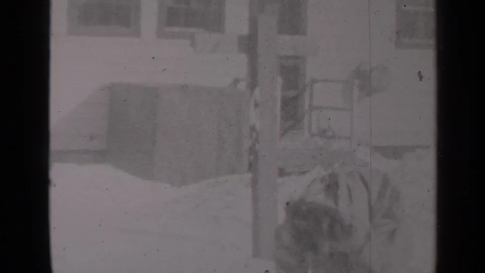 1947 New York frame showing a man bent over with a shovel near snow and a residential entry area.