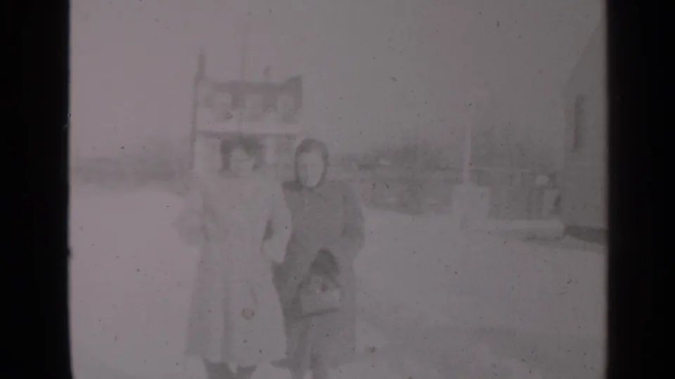 The women remain close together in heavy coats on a snow-covered New York street, with background buildings faintly visible.