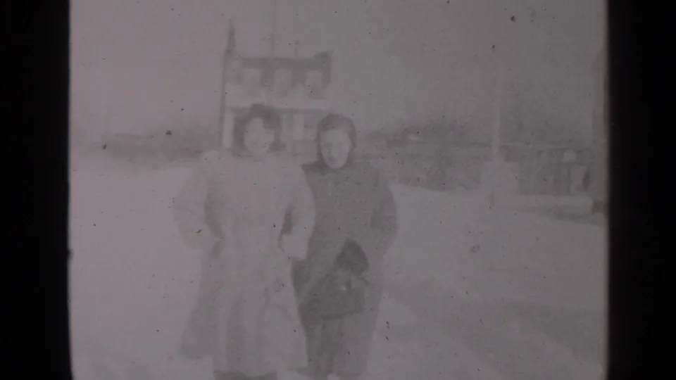 A closer 8mm frame shows the two women bundled against the cold as they move along the snow-covered street.