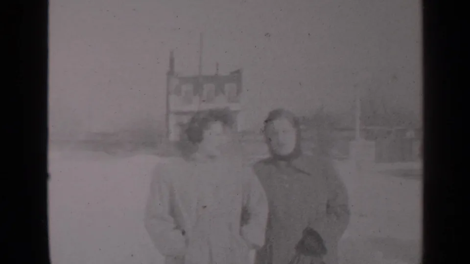 Two women in winter coats approach the camera on a snowy New York street, consistent with the supplied 1947 home-movie metadata.