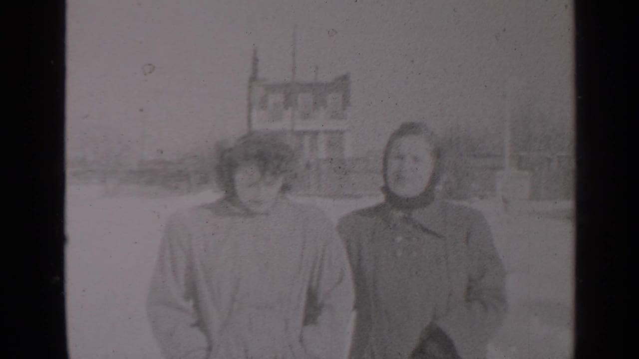 Two women in heavy coats face the camera while walking on a snowy street.
