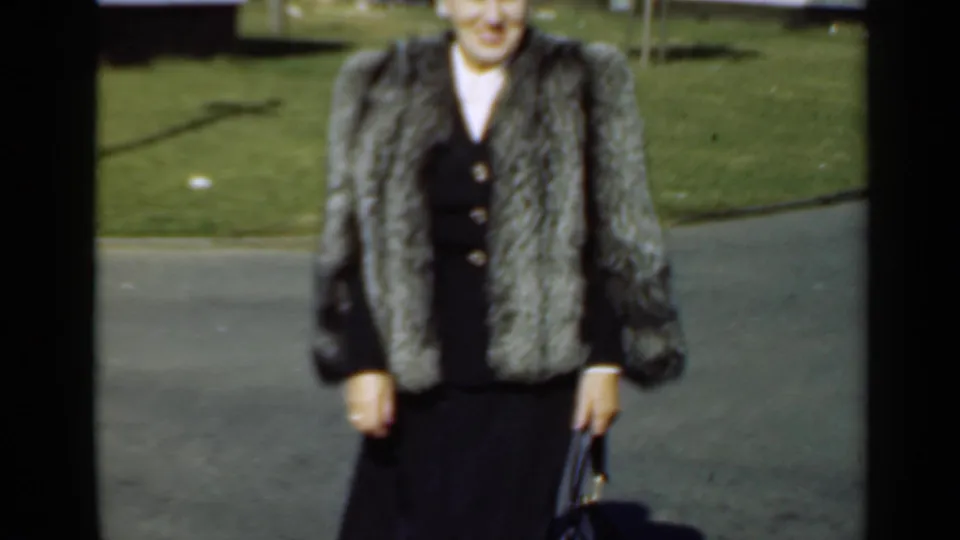 A closer 8mm frame shows the woman’s silver-gray fur coat, dark dress, and handbag as she moves toward the camera in New York, 1947.