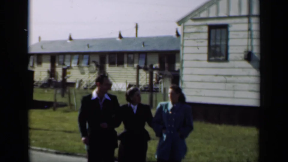 Three well-dressed adults walk toward the camera on a lawn in 1947 New York residential footage.