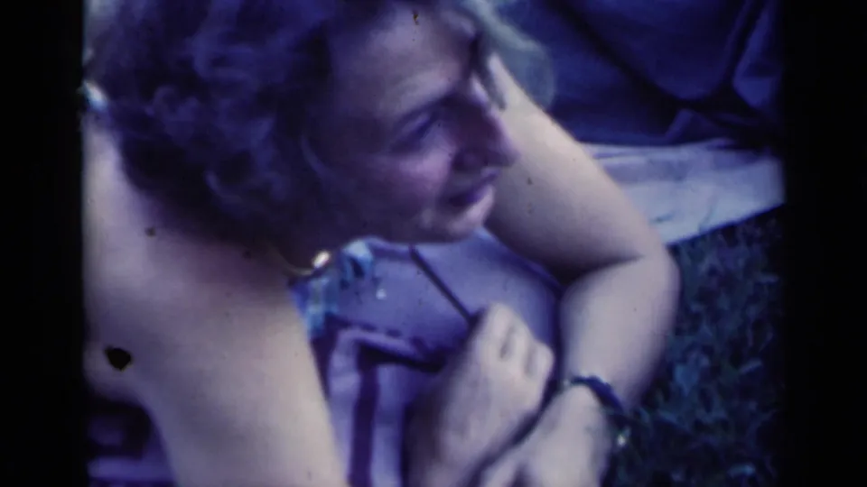 Close home-movie view of a woman smiling on grass, with another person partly visible beside her in the 1948 Indiana clip.