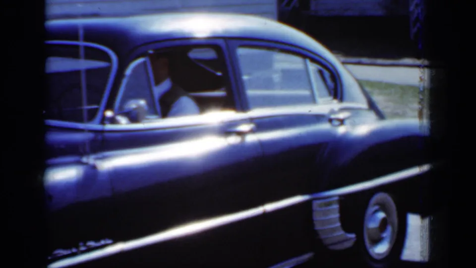 1950 New York 8mm frame showing the side windows, driver area, rear door, and whitewall-style tire of a classic sedan.