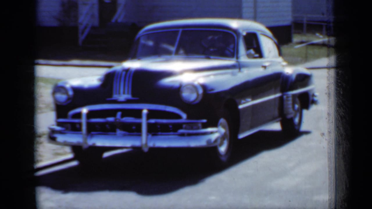 Black sedan facing the camera with chrome grille and bumper visible.