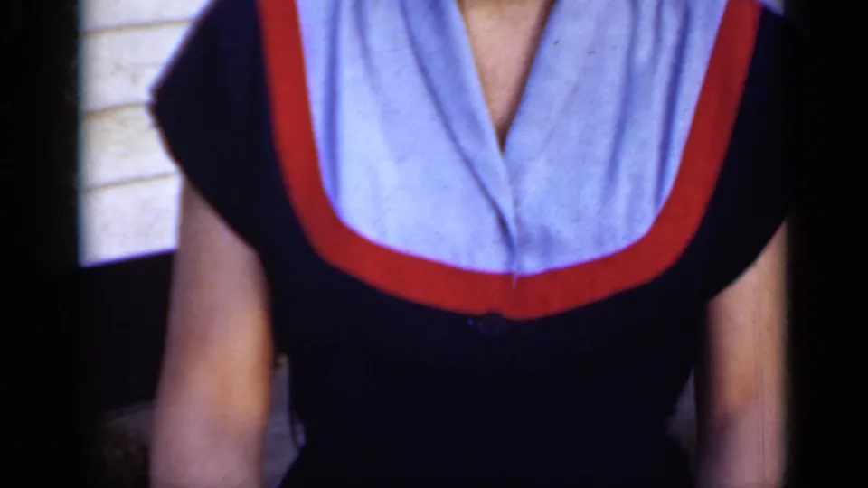 Cropped 1950 New York home-movie frame showing the upper body of a person in a blue outfit with a light blue and red collar.