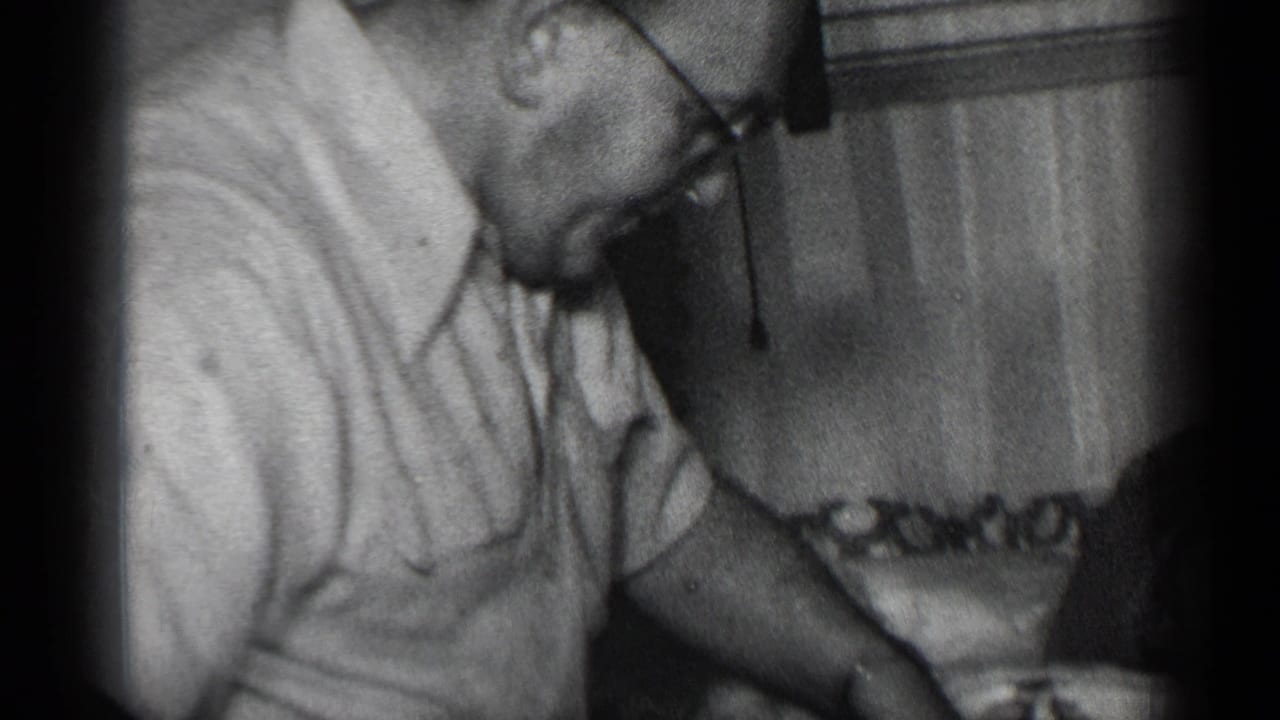 Man in glasses bends over the table with his hand near meat and a knife.