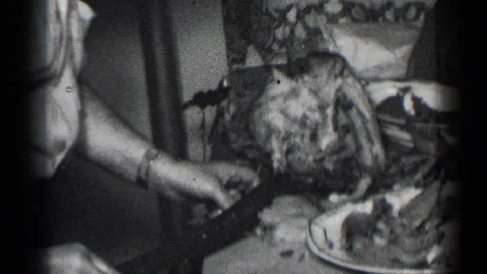 Hands carve a large roast turkey at a 1950 New York family meal, with plates and tableware close by.