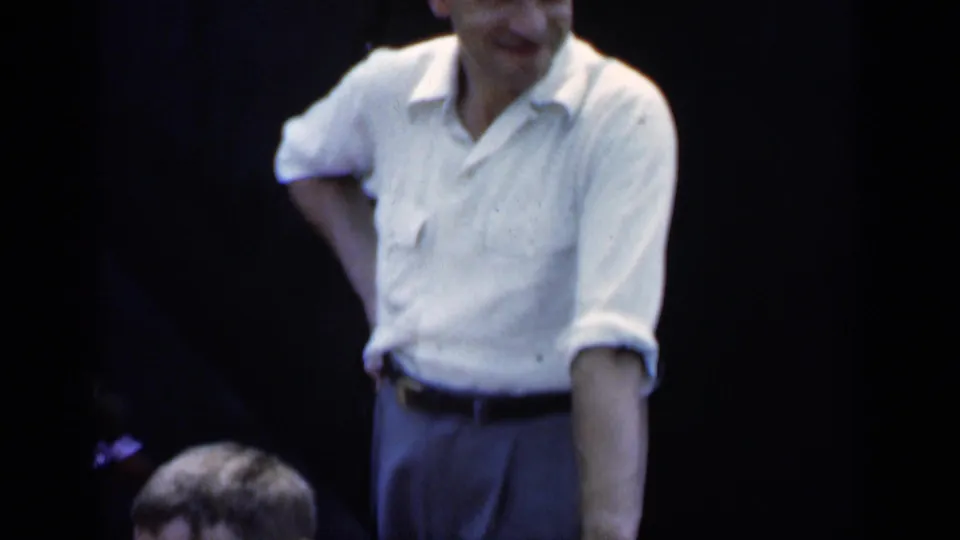 1951 New York home-movie frame showing a casually dressed man outdoors with another person's head partly visible near the bottom edge.