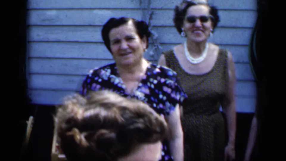 In the stated 1951 New York scene, a smiling woman stands before a second woman wearing sunglasses and pearls.