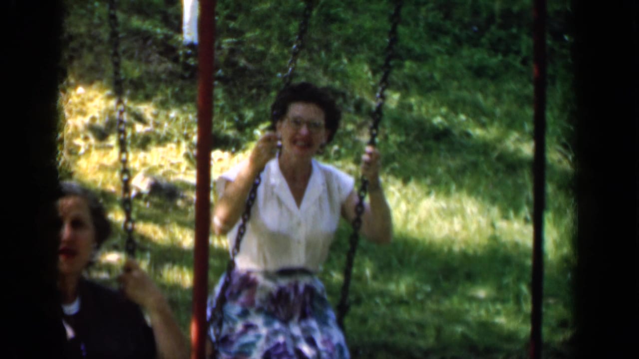 Woman on a swing with another person partly visible nearby.