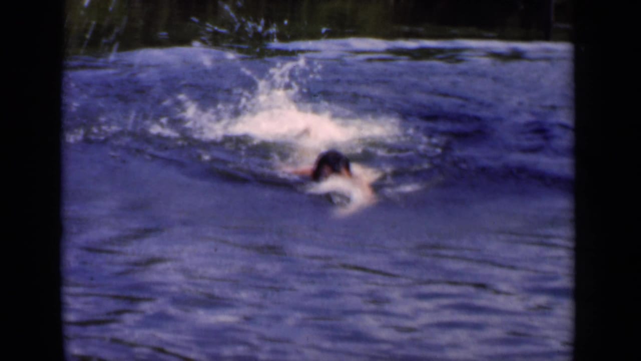 Adult swimmer partly submerged as water splashes around his head and arms.