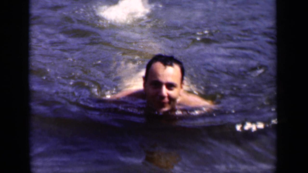 Smiling adult man floating or swimming in open water.