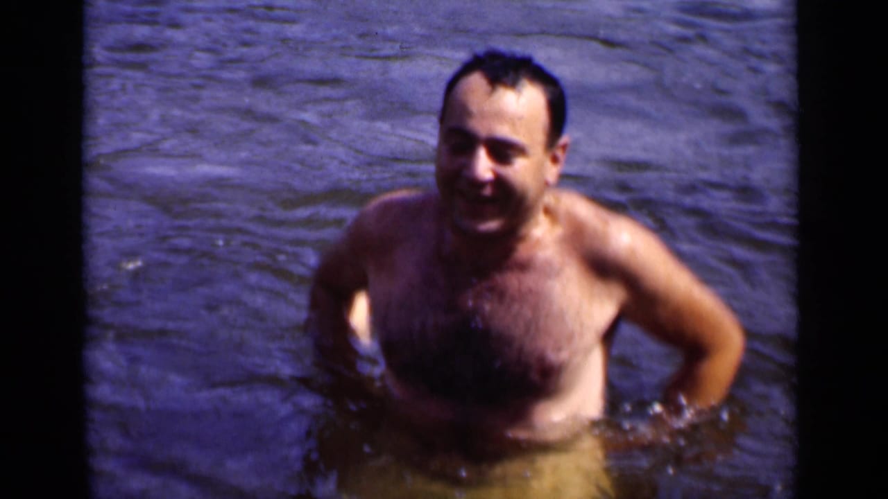 Smiling adult man standing chest-deep in rippling water.