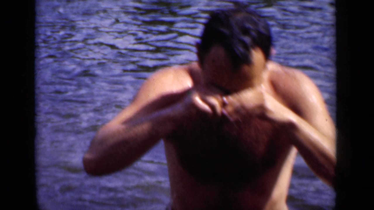 Adult man in water rinsing or wiping his face with both hands.