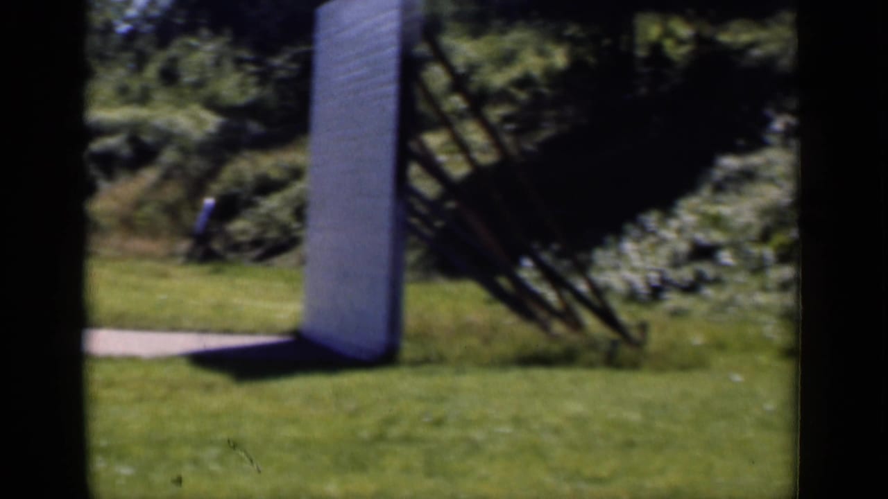 1951 New York outdoor frame with a large white upright structure on the grass, trees, shrubs, and a nearby angled frame.