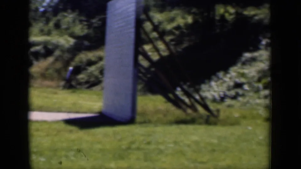 1951 New York outdoor frame with a large white upright structure on the grass, trees, shrubs, and a nearby angled frame.