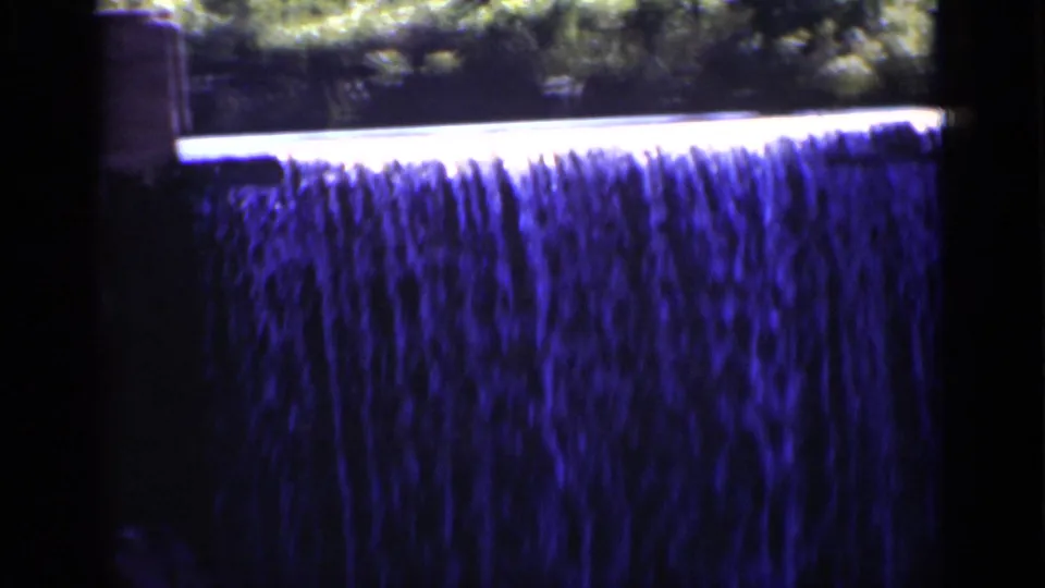 1951 New York home-movie close-up of a cascading waterfall, with bright sunlight along the top and blue-purple water tones.