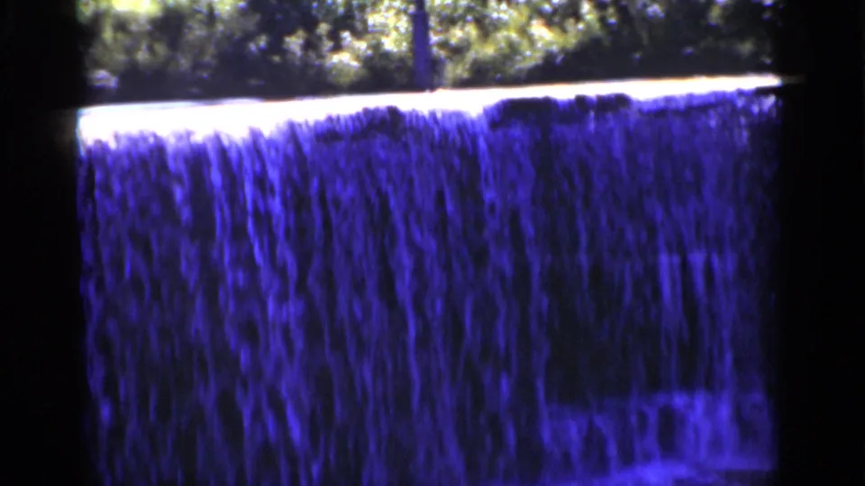 1951 New York 8mm frame with a broad blue waterfall filling most of the view, bordered by trees and dark scan edges.