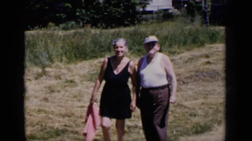 In metadata-supported 1951 New York home-movie footage, an older woman in a dark dress and an older man in a cap walk together outdoors.