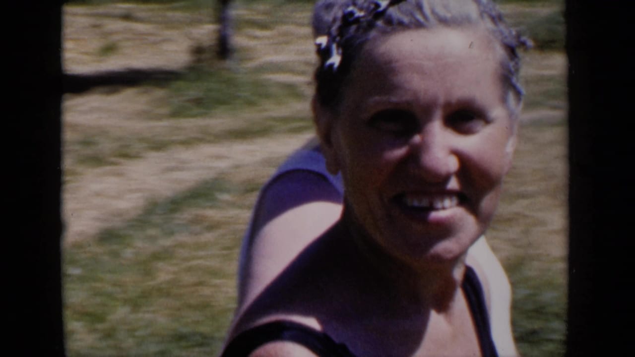 In 1951 New York home-movie footage, a woman in a white swim cap and dark swimsuit smiles near an outdoor pool.
